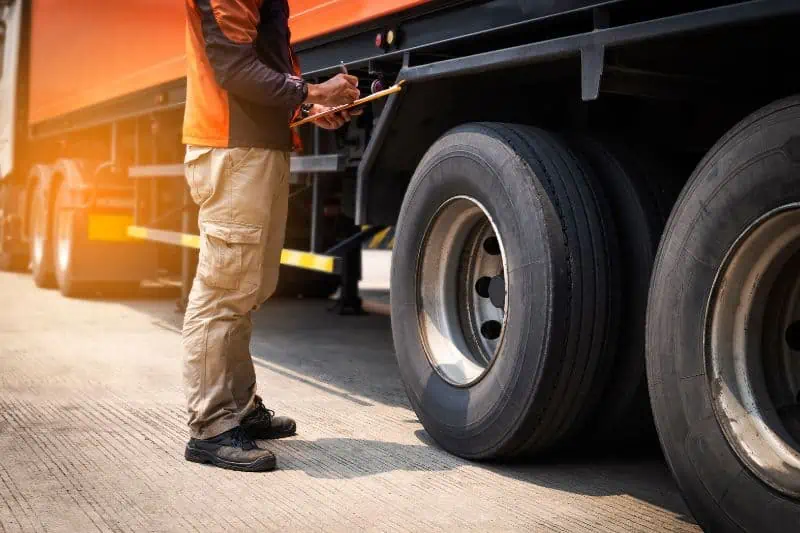 un agente de inspeccion mirando las gomas del camion